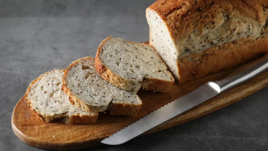 Tranches de pain aux graines et couteau à pain sur une planche en bois